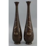 A pair of Chinese bronze vases, each of slender bottle shaped form chased and inlaid with white