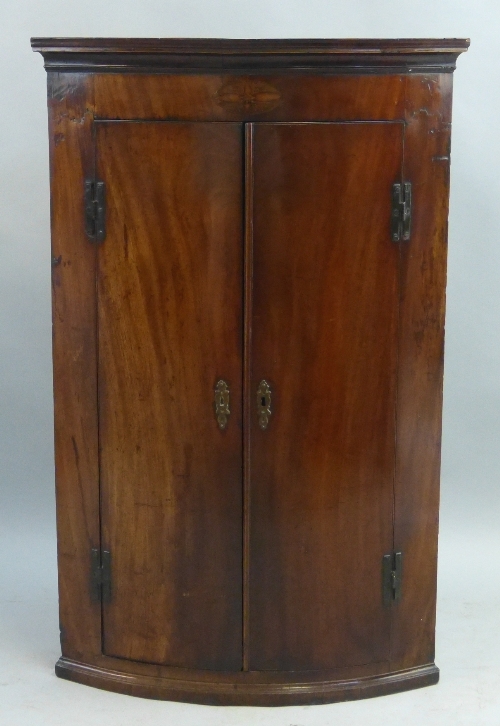 An early 19th Century mahogany quadrant corner cupboard, wall hanging with flared cornice over an