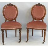 A pair of 19th Century walnut framed salon chairs, the circular upholstered back with leaf carved