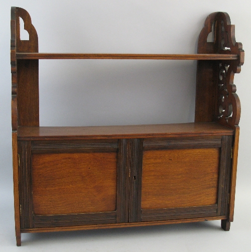 An early 20th Century walnut cupboard, wall mounting with pierced sides and single open shelf over