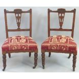 A pair of late 19th Century walnut framed salon chairs, having arched crest rails on line incised