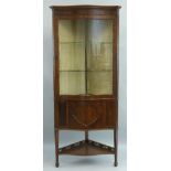 An early 20th Century mahogany corner display cabinet, floor standing of serpentine form with flared