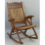 A late 19th Century oak rocking chair, with leaf carved crest rail over square padded back, padded