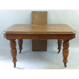 An Edwardian oak extending dining table, with one leaf, the wind out moulded edged canted top on