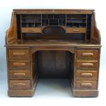 An oak roll top desk, the tambour front opening to reveal pigeon holes and drawers, the base with