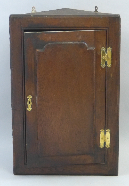 A 19th Century oak corner cupboard, wall hanging with panelled door enclosing shelves, 76cm high,