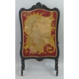 A Victorian ebonised fire screen, having gros and petit point oblong panel in leaf carved surround
