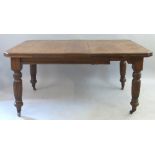 A late 19th Century oak extending dining table, the wind out canted oblong top with one leaf on