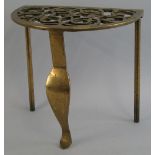 A 19th Century brass trivet, in the form of a semi circular footman with pierced scrolling top and