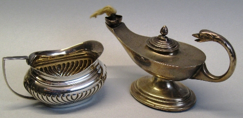 An oil lamp, of oval pedestal form with bird's head flying scroll handle, lift off stepped lid