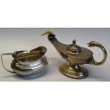 An oil lamp, of oval pedestal form with bird's head flying scroll handle, lift off stepped lid