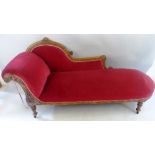 A Victorian walnut framed chaise longue, the upholstered arched back incised with flowers, scroll