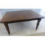 An Edwardian extending dining table, with one leaf and wind out action, the stained canary wood