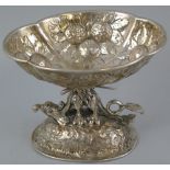 A continental salt, the quatrefoil shaped bowl embossed with fruit, on a dragon style winged