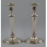 A pair of Edwardian candlesticks, each with reeded oval drip pan on fluted urn sconce, tapering