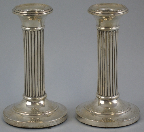 A pair of Edwardian candlesticks, with slightly dished tapering sconces on reeded circular columns