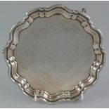 A card waiter, of shaped circular form with moulded Chippendale style rim raised on three
