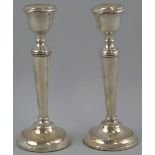 A pair of candlesticks, with urn shaped sconces on tapering cylindrical columns and stepped circular