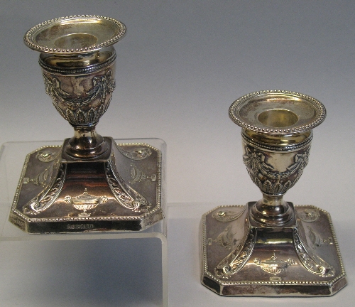 A pair of Victorian dwarf candlesticks, each with beaded circular drip pan and urn shaped sconce