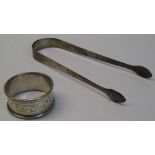 A George III pair of bow sugar tongs, of plain tapering form London 1814 and a napkin ring of
