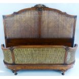 A French walnut king sized bedstead, the arched headboard with shell carved crest and single cane