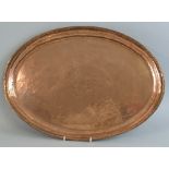 An Arts & Crafts copper tray, by Hugh Wallis of beaten oval form with chased flower to the centre,