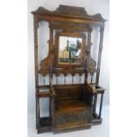 A Victorian oak hall stand, carved all over in the Jacobean style with scrolling pediment and