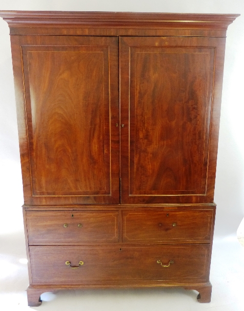 A George III mahogany linen press, with box wood stringing, flared cornice over two panelled doors