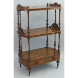 A Victorian walnut whatnot, comprising three oval tiers on baluster turned and reeded supports