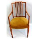 An Edwardian satinwood elbow chair, with stepped crest rail over an open back with five tapering