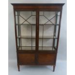 An early 20th Century mahogany display cabinet, with moulded cornice and plain frieze over a pair of