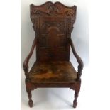 An oak wainscot chair, in the 17th Century style, the undulating crest rail carved with a pair of