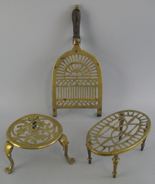 A Victorian brass trivet, of pierced D-shaped form with turned wooden handle and three iron feet,