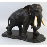 A Japanese Meiji period bronze figure, of a standing elephant, with fitted ivory tusks, cast with