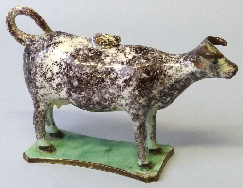 A 19th century sponged creamware cow creamer, with tail loop handle and lid, on green glazed