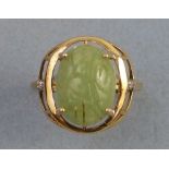 A jade and diamond ring, having carved jade oval cabochon in open framework with diamond set