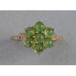 An emerald and diamond ring, having a cluster of seven cabochon emeralds in a flowerhead setting