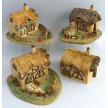 Two stoneware models of cottages, with fenced front gardens, 24cm long, another similar with