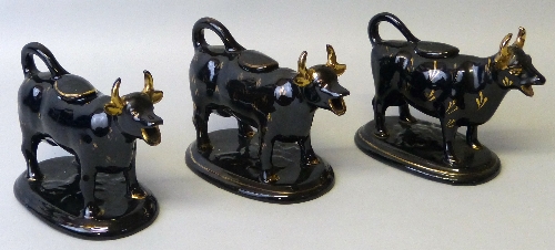 Three 19th century Staffordshire black glazed cow creamers, each with tail loop handle and lid and