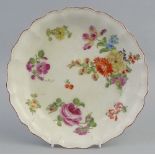 An 18th century dish in the Chelsea style, of shallow circular form with wavy rim, the centre