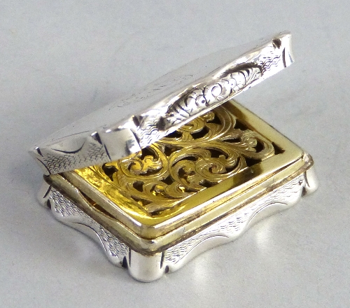 A Victorian vinaigrette, of chased oblong form with scrolling rim, the monogrammed hinged lid