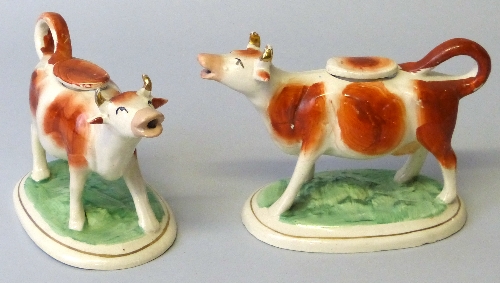 Two 19th century Staffordshire cow creamers, each with tail loop handle and lid, painted with