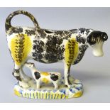 A 19th century cow creamer and calf group, with tail loop handle painted and sponged in black and