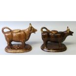 Two 19th century earthenware cow creamers, each with tail loop handle and lid, and brown glazed with
