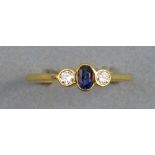 A sapphire and diamond ring, comprising central oval sapphire, flanked by a diamond to each side