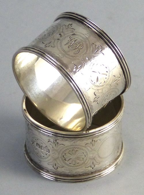 A pair of Victorian napkin rings, each of circular form with raised reeded rim, chased centre and