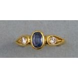 A sapphire and diamond ring, comprising central oval sapphire, flanked by a shoulder set diamond