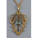 An Edwardian pendant, with central aquamarine coloured stone surrounded by an open scrolling