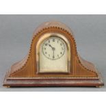 A bedroom timepiece with arched silvered dial and Arabic numerals contained in an inlaid oak arch