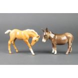 A Beswick figure of a standing donkey 5 3/4", a ditto of a foal 7"The donkey has a flaw on the